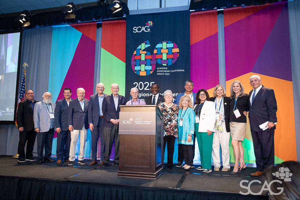 Group of people standing on stage in front of colorful backdrop.