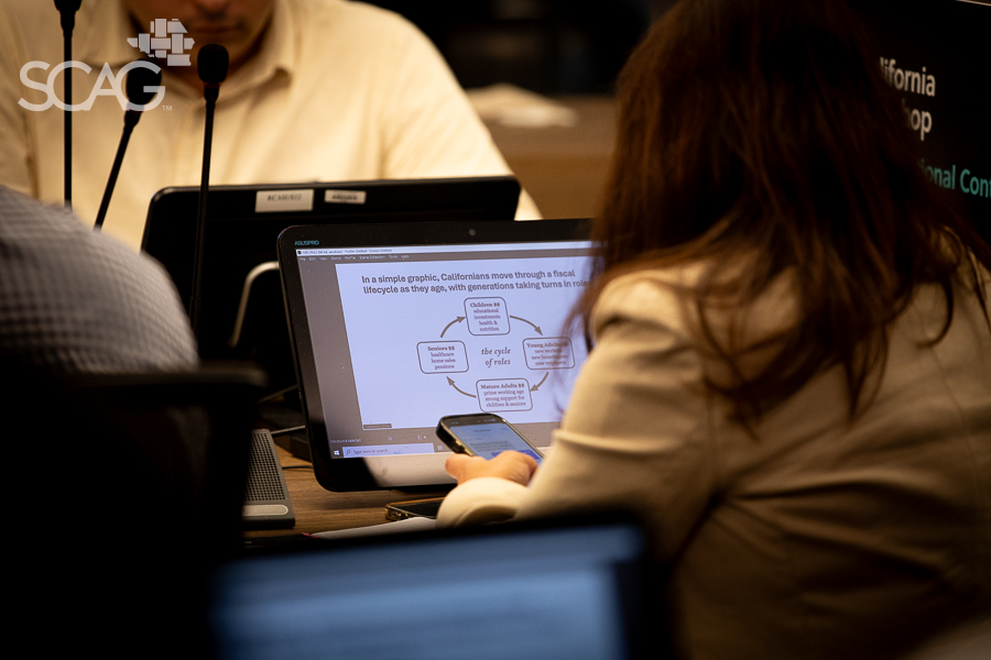 Person viewing a presentation on a laptop in a conference setting.